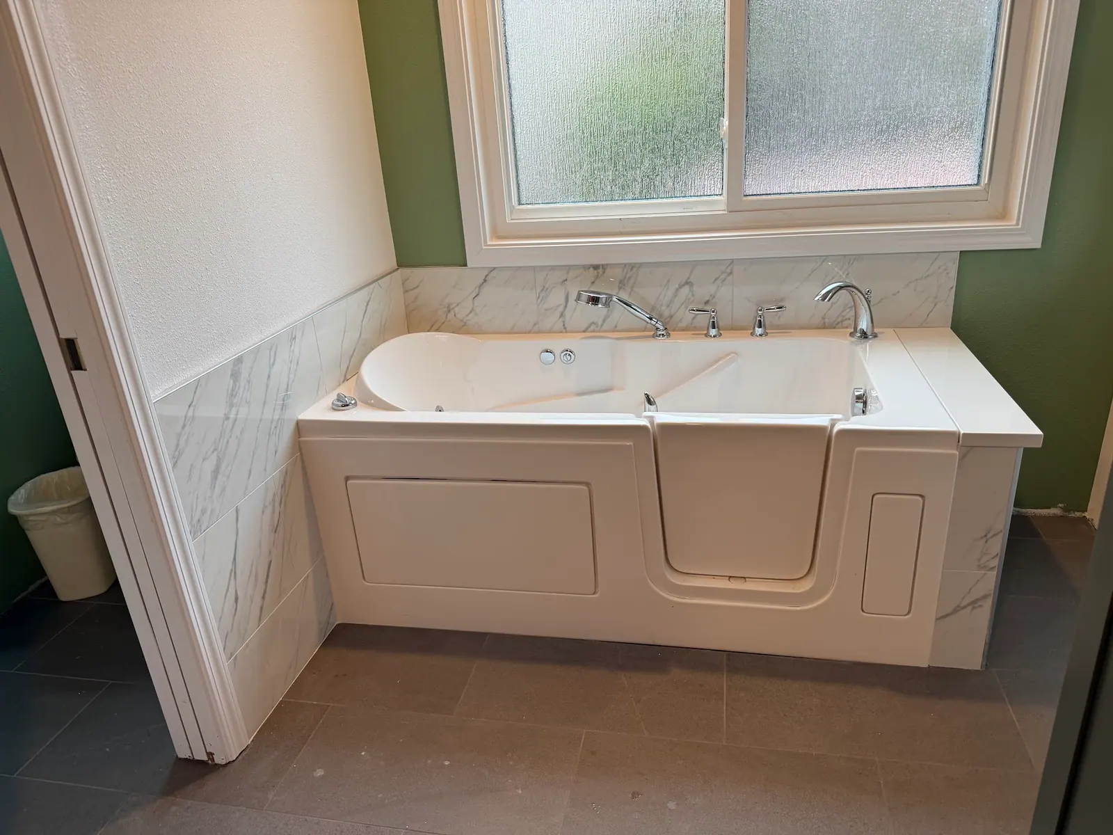 Walk-in bathtub with marble-look wall panels